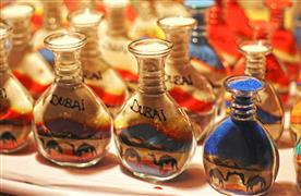 سوغات دبی؛ تصویری از چند شیشه‌ی پُر شده با شن‌های رنگی که واژه‌ی «Dubai» روی‌شان نوشته شده.